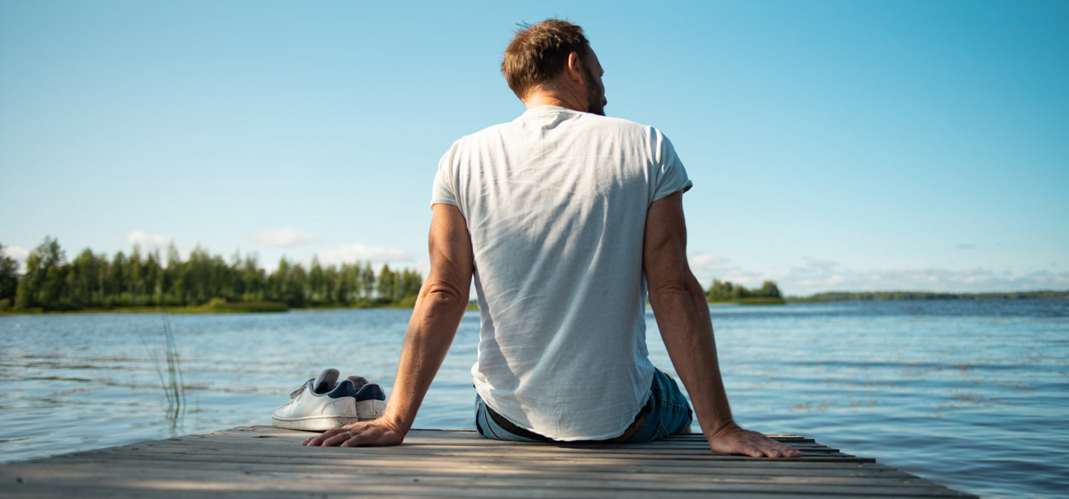 Mann sitzt am See während seines Sabbaticals